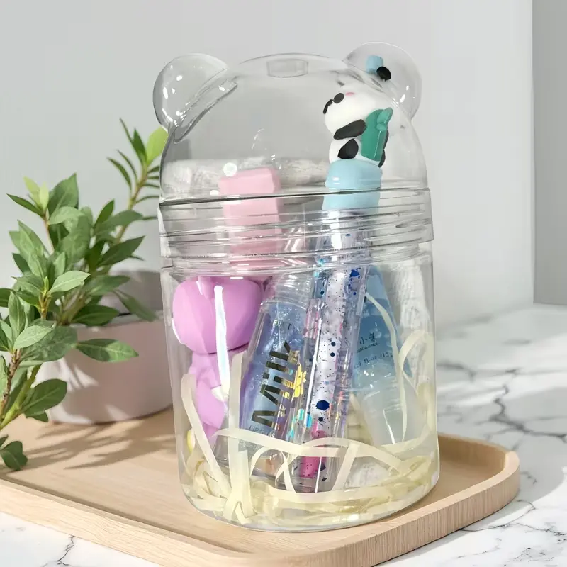Aesthetic transparent bear-shaped jar filled with blue and pink lip gloss tubes on a wooden tray.