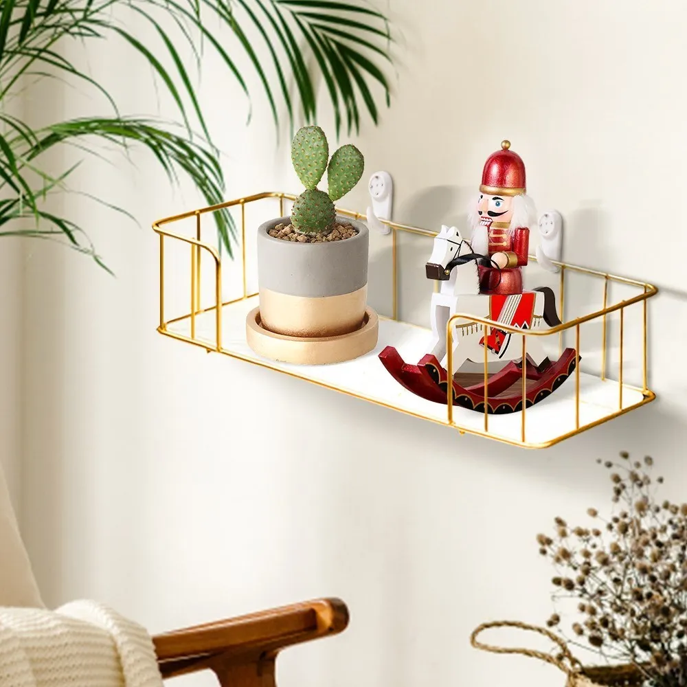 Gold iron shelf with cactus and nutcracker on a white wall.