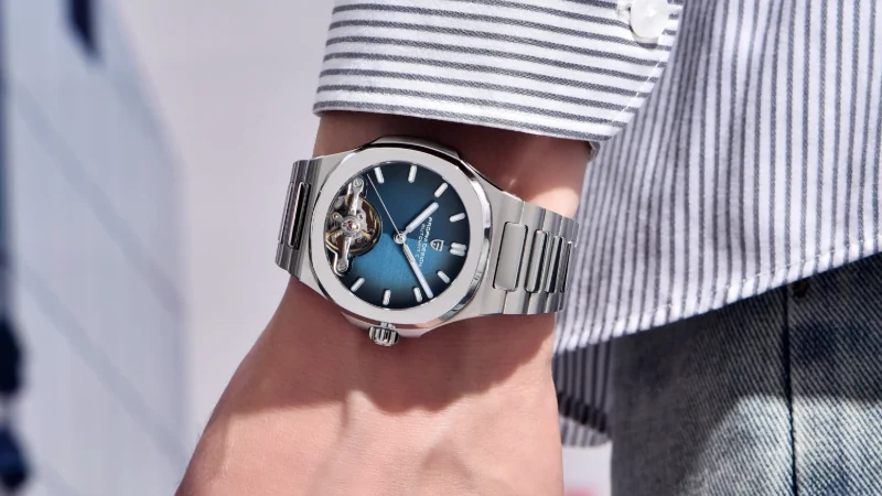 A close-up of Pagani Design blue dial skeleton watch worn with a striped shirt and blue jeans.