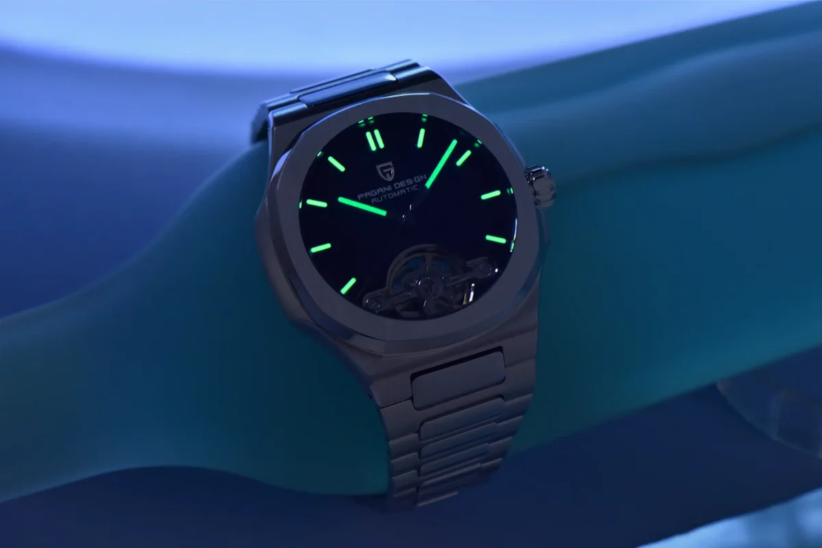 Dark view of Pagani Design watch showing the green luminous hands and hour markers in low light.