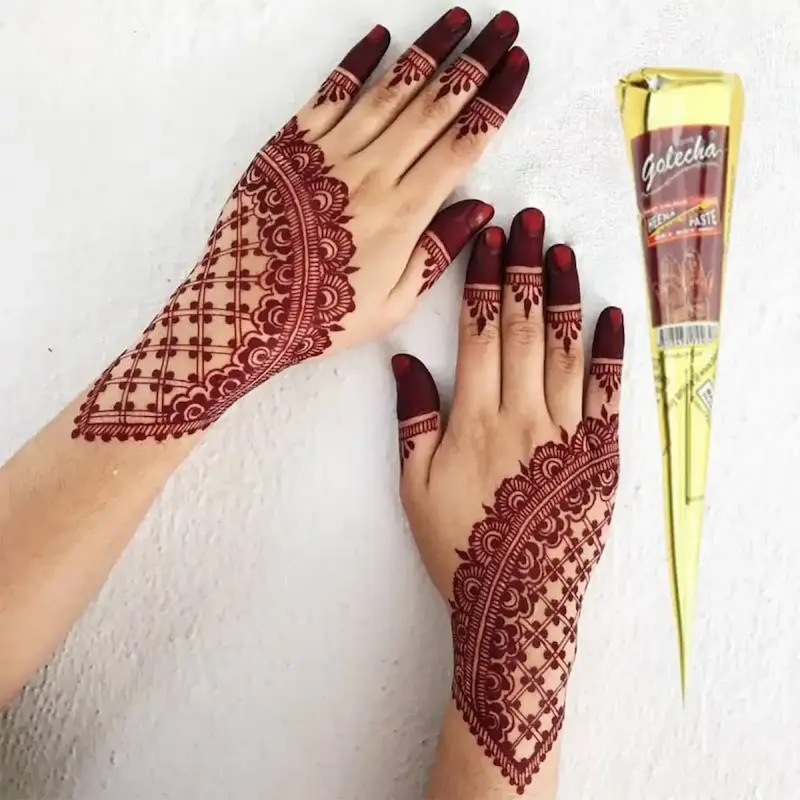 Elegant maroon bridal mehndi pattern on both hands next to a gold Golecha cone, representing the best temporary henna cones for traditional designs.
