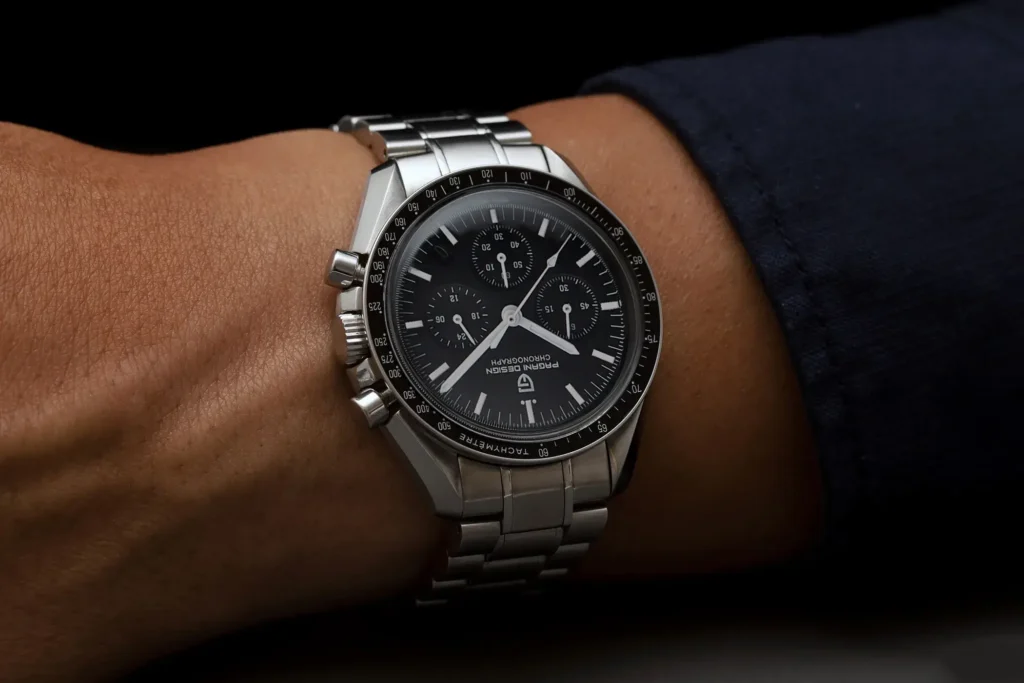 Close-up wrist shot of a Pagani Design PD-1701 Moonwatch homage with a black chronograph dial and steel bracelet.