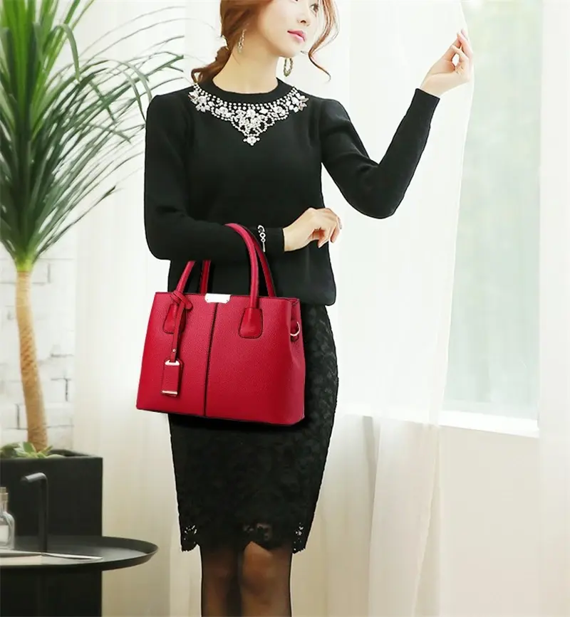 Elegant woman in a black dress carrying a red leather handbag in an indoor setting