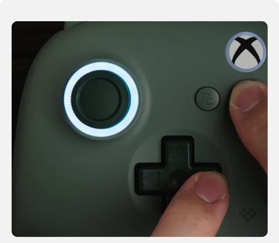 Close-up of the tactile D-pad and buttons on the 8BitDo Dark Green controller with blue RGB lighting.