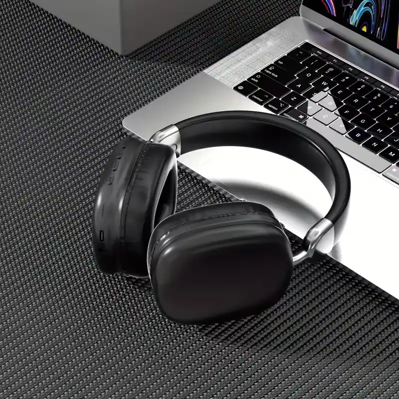 Sleek black wireless earphones sitting next to a professional laptop keyboard.