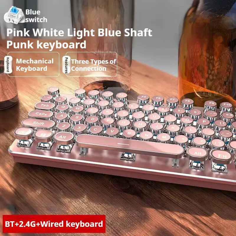 A close-up view of a pink retro typewriter style mechanical keyboard with white backlighting on a wooden desk.