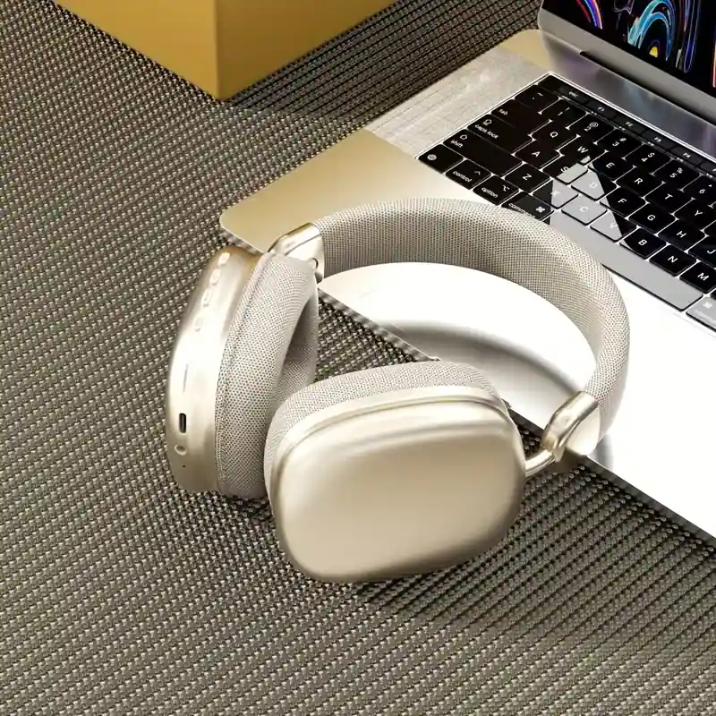 Premium gold-colored wireless headphones on a textured desk surface.