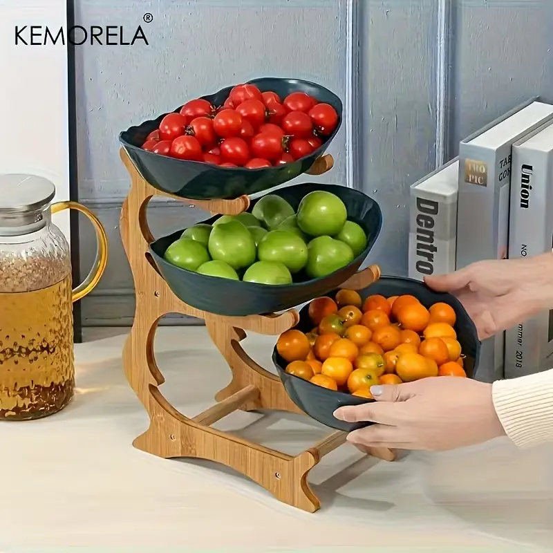 Dark green KEMORELA 3-tier kitchen organizer filled with fresh fruits on a wooden stand.