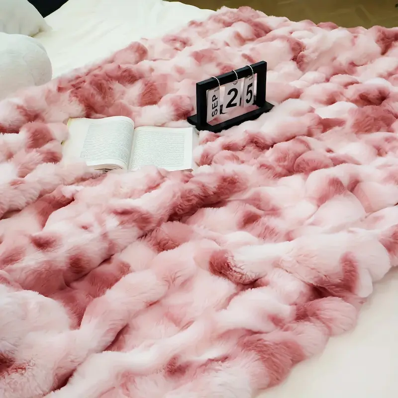 Close-up of a pink and white patterned soft fleece blanket with a book and calendar.