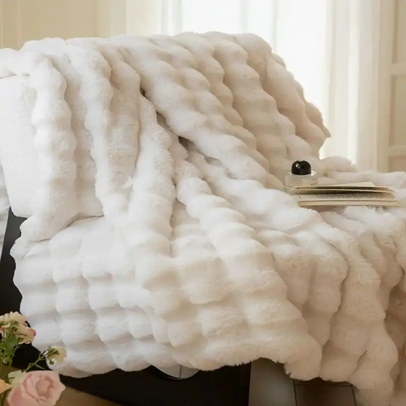 A pure white textured fluffy fleece blanket with a wavy pattern displayed on furniture.