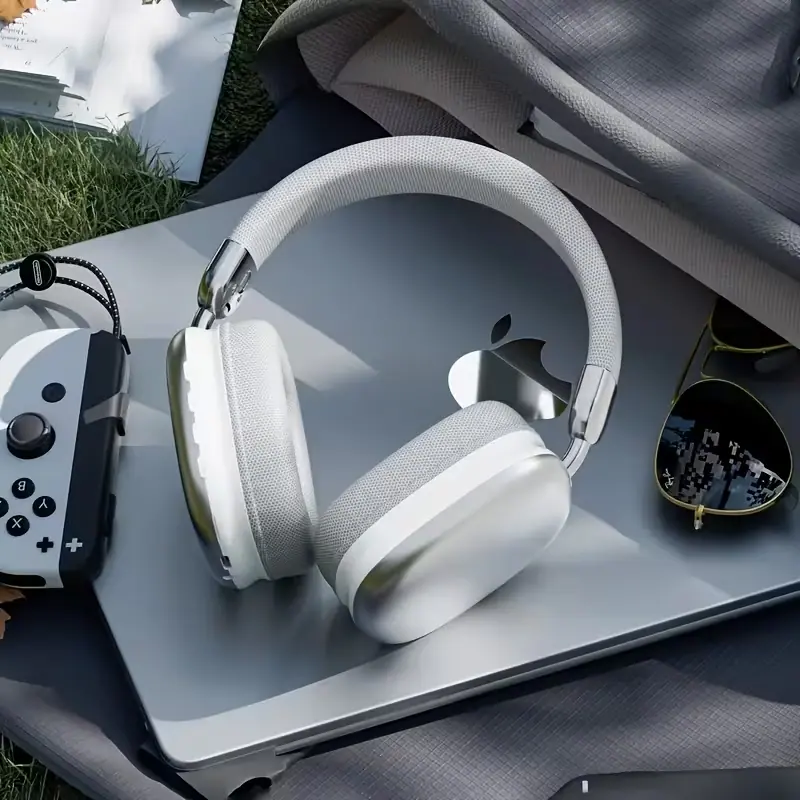 Elegant white wireless headphones placed on a laptop in an outdoor setting.