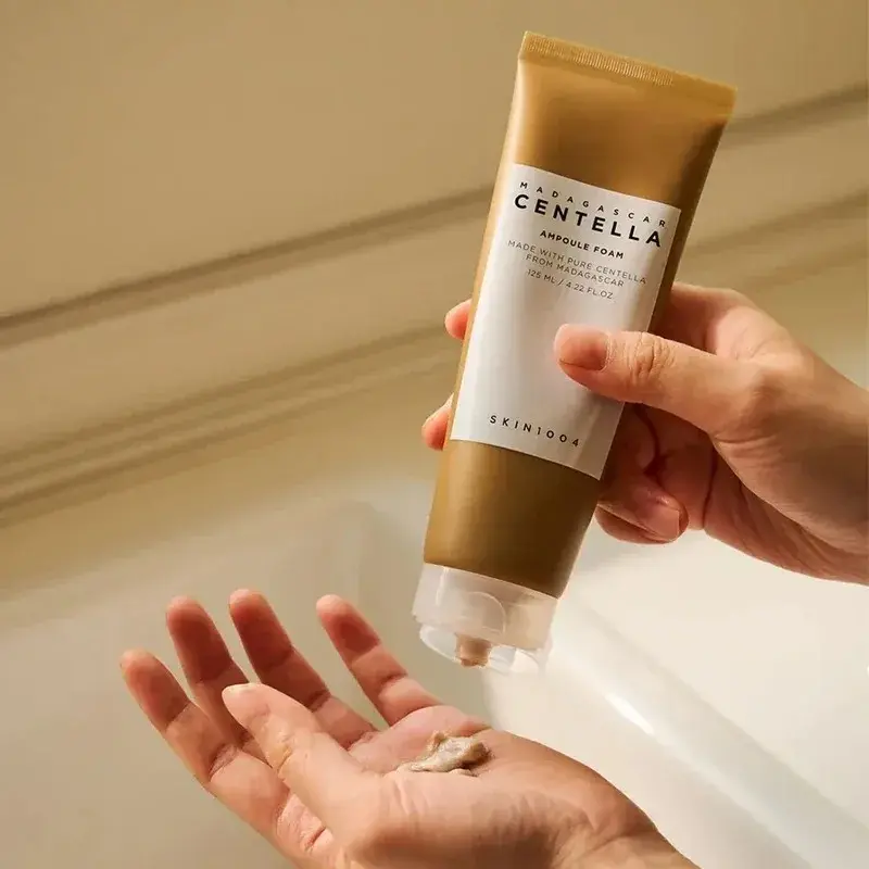 A person squeezing the brown Ampoule Foam cleanser onto their palm.