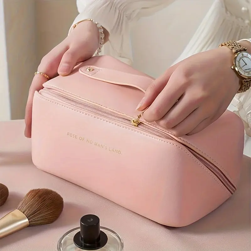Close up of hands zipping up a premium pink leather makeup organizer with a gold zipper.