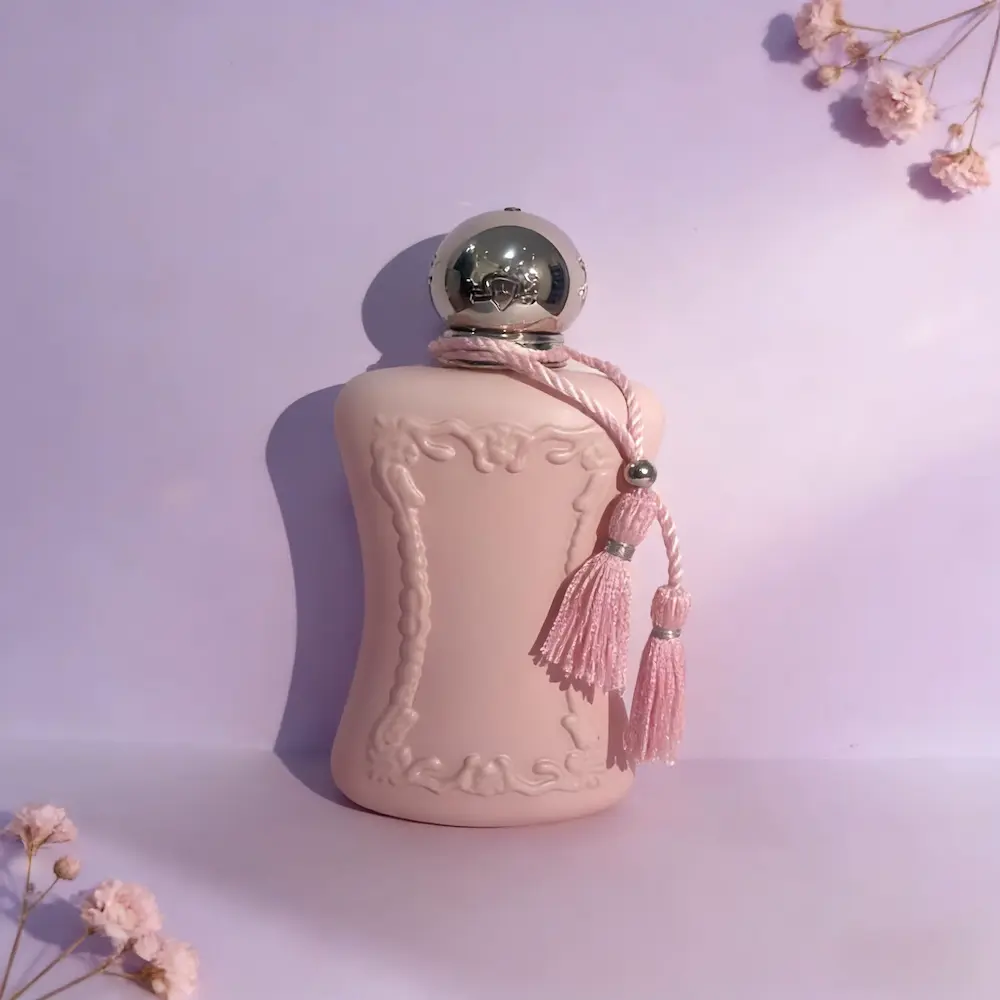 A minimalist view for our Delina EDP Scent Review showing the elegant pink bottle set against a soft purple backdrop with flowers.