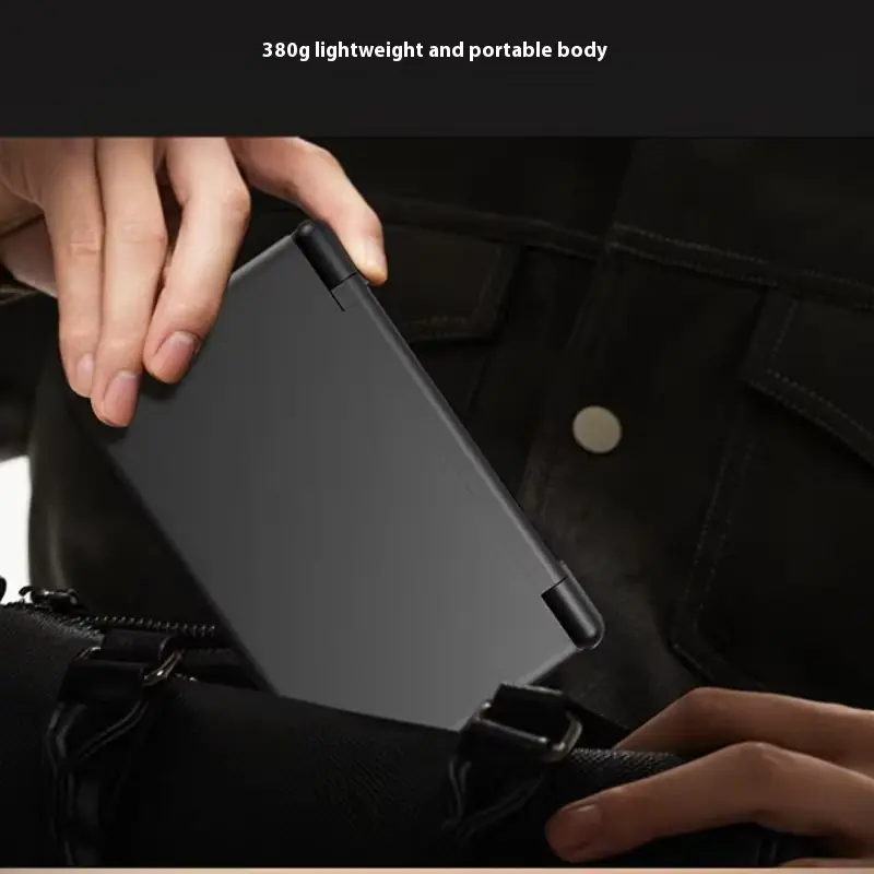 Black clam shell gaming console being placed inside a shoulder bag by hand.
