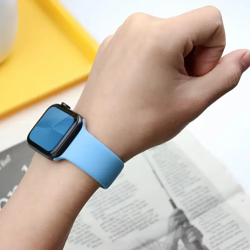 A person wearing a light blue silicone Apple Watch band on their wrist.