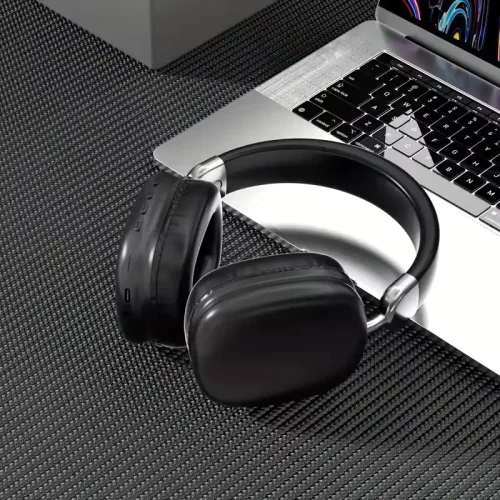 Sleek black wireless earphones sitting next to a professional laptop keyboard.